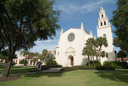 exterior of church with large bell tower and well manicured lawn.