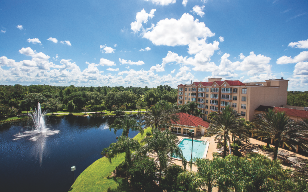A landscape view of The Mayflower at Winter Park with our lake, pool, and building.