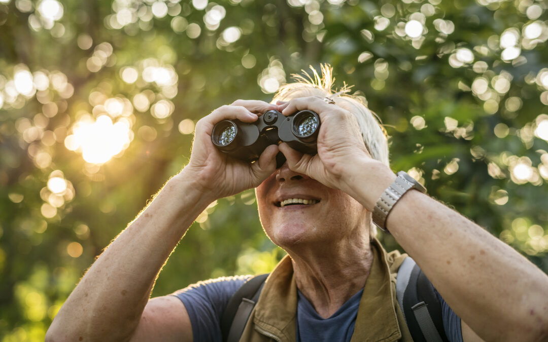 a senior woman hiking while using binoculars