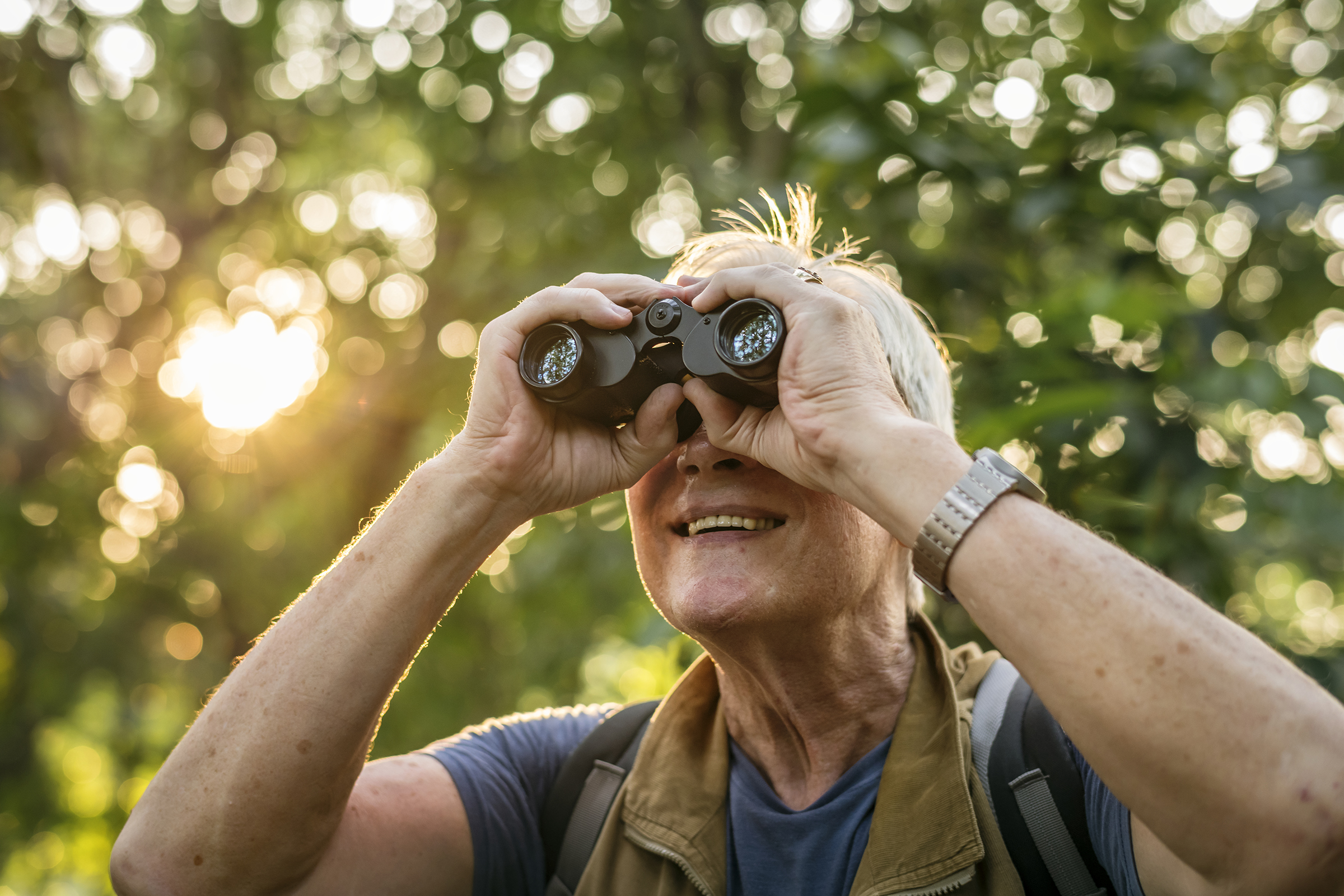 a senior woman hiking while using binoculars