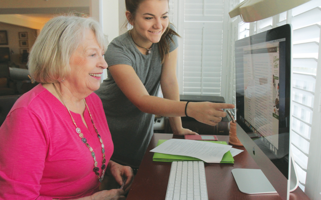 Senior woman smiles with a younger woman at a computer screen