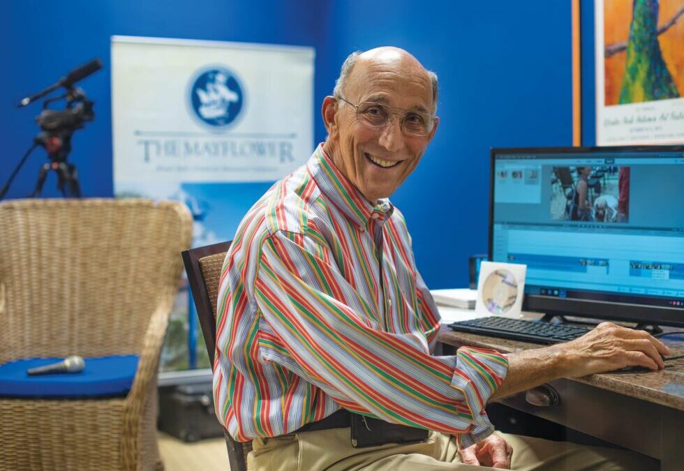 A senior man smiles with his computer.