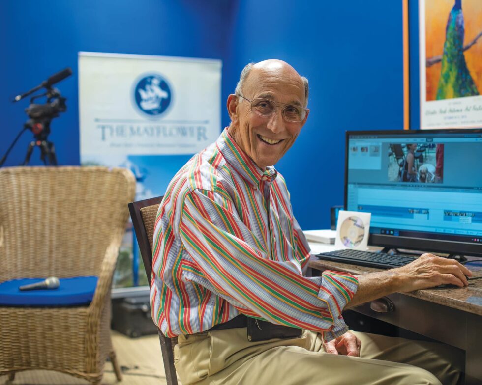 A senior man smiles with his computer.