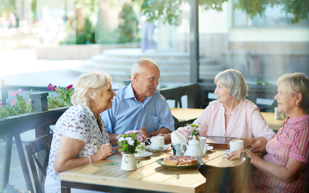 Four seniors gathered around lunch on a lovely patio.