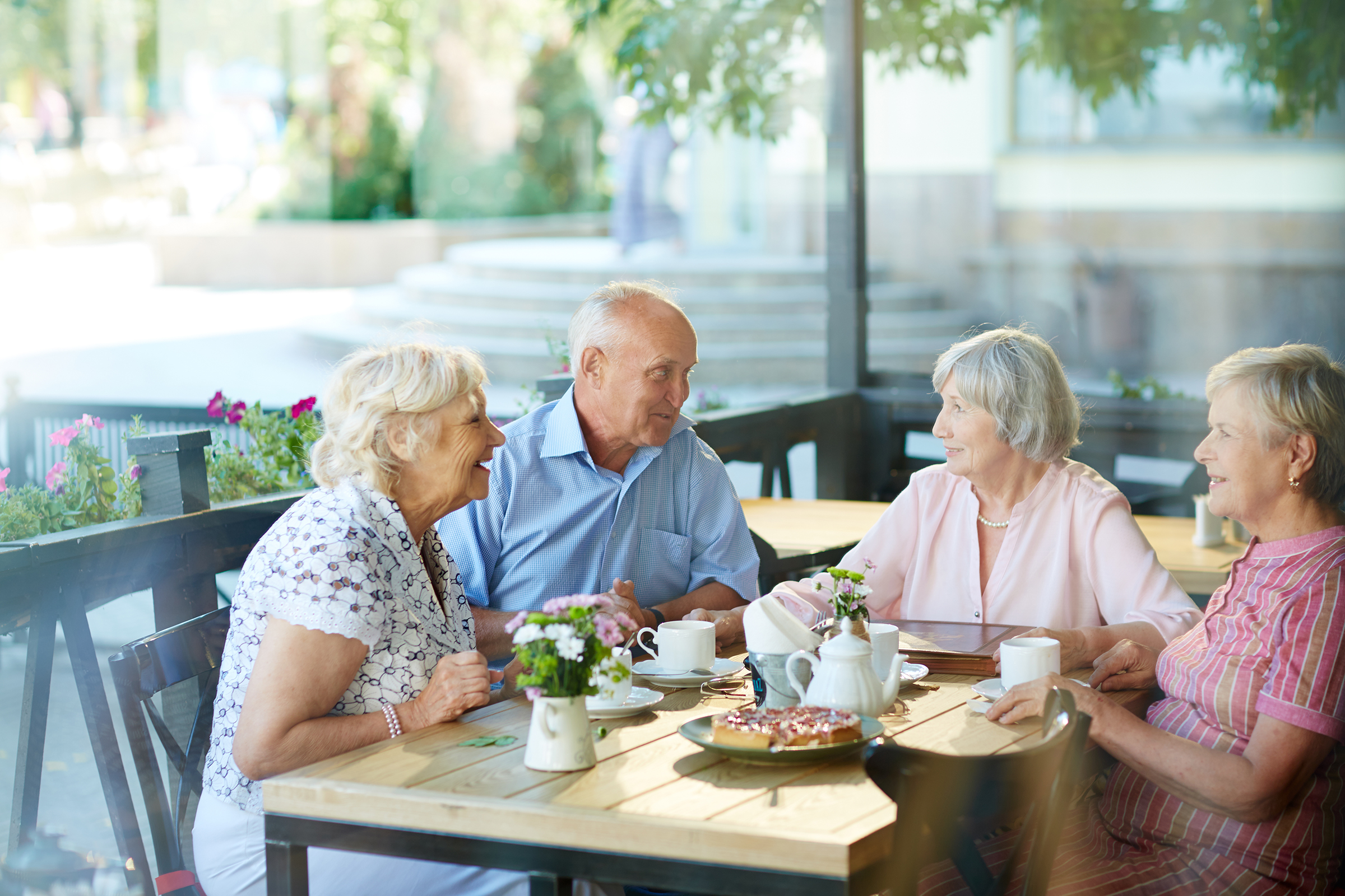 Four seniors gathered around lunch on a lovely patio.