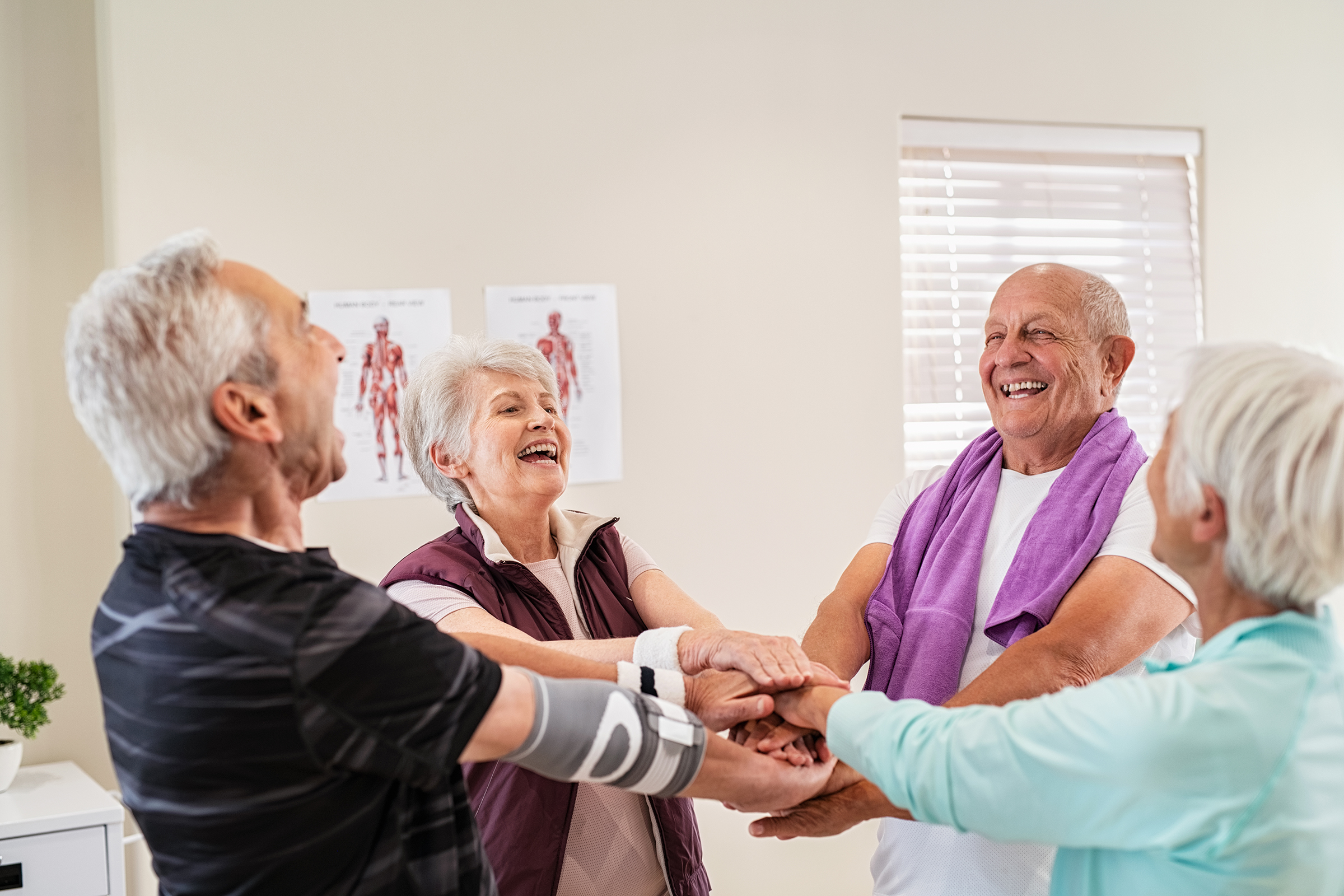 Laughing senior people putting hands together after workout.