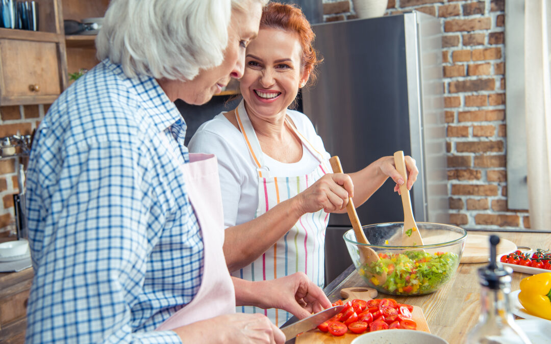 Smiling women in aprons cooking together in kitchen