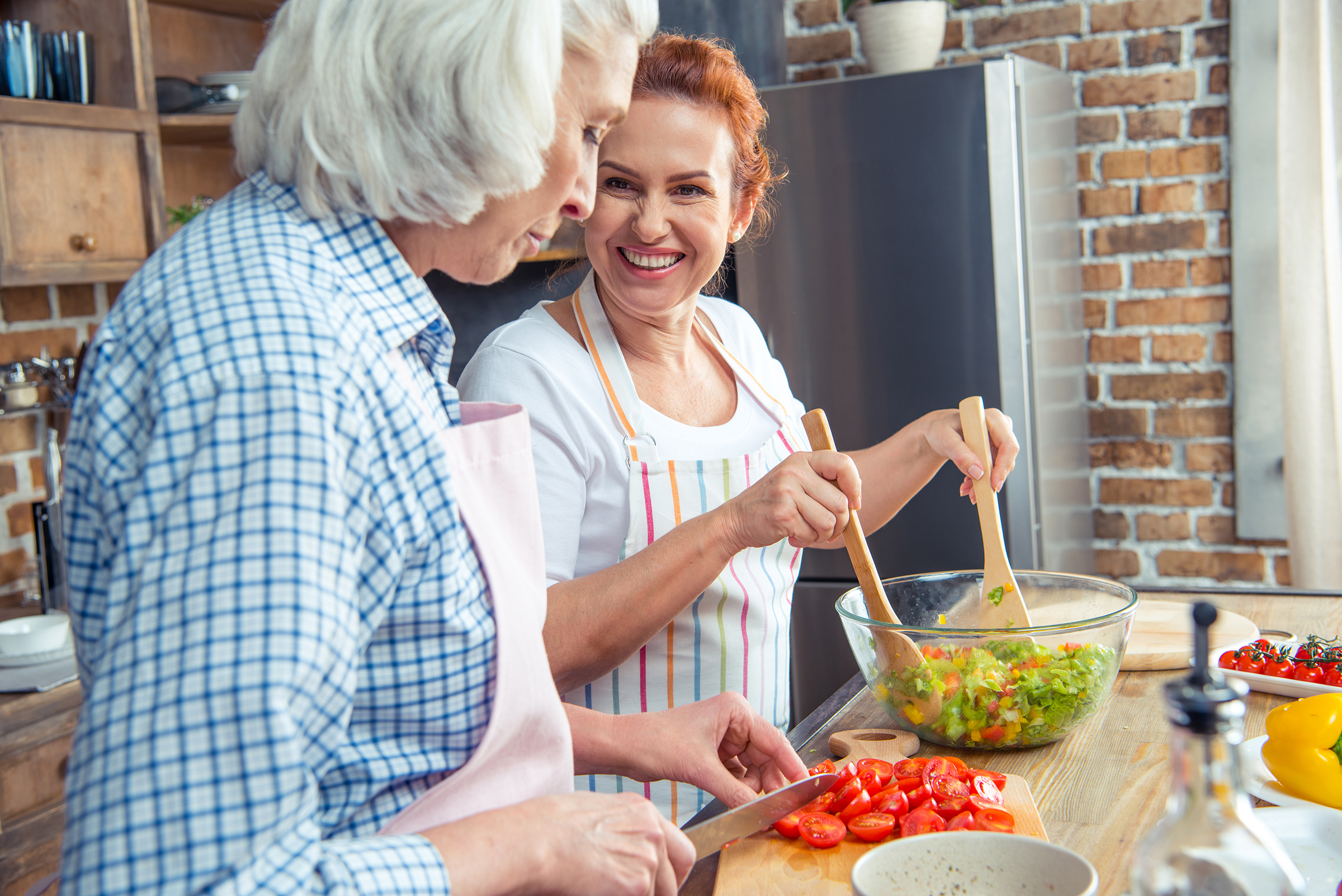 Smiling women in aprons cooking together in kitchen